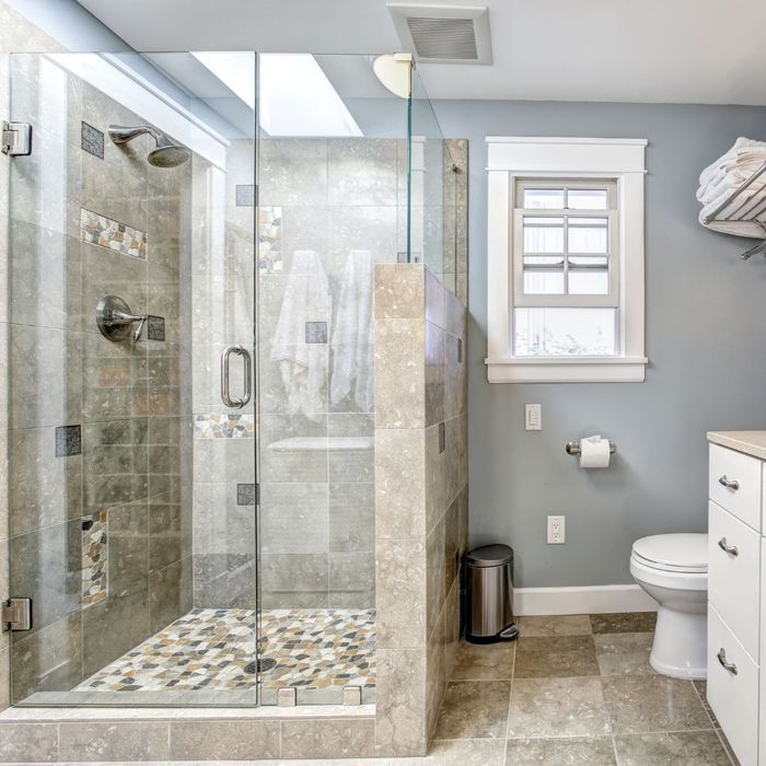 Frameless shower enclosure for stone tiled shower